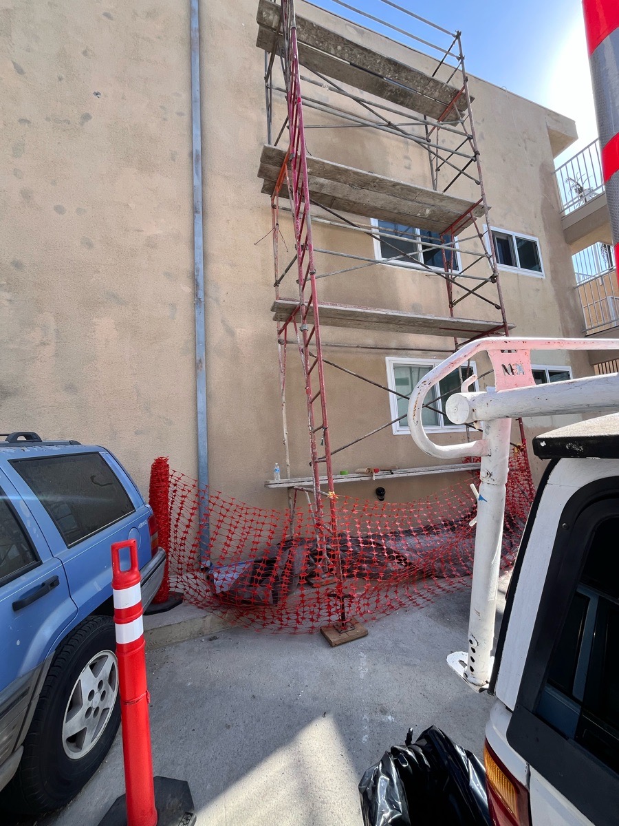 Scaffold and controlled work area at a multi-story exterior stucco wall